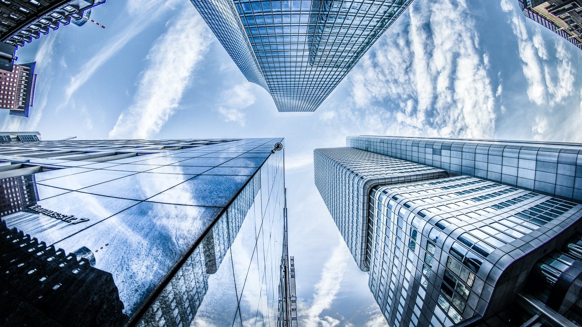 low angle photo of four high rise curtain wall buildings under white clouds and blue sky